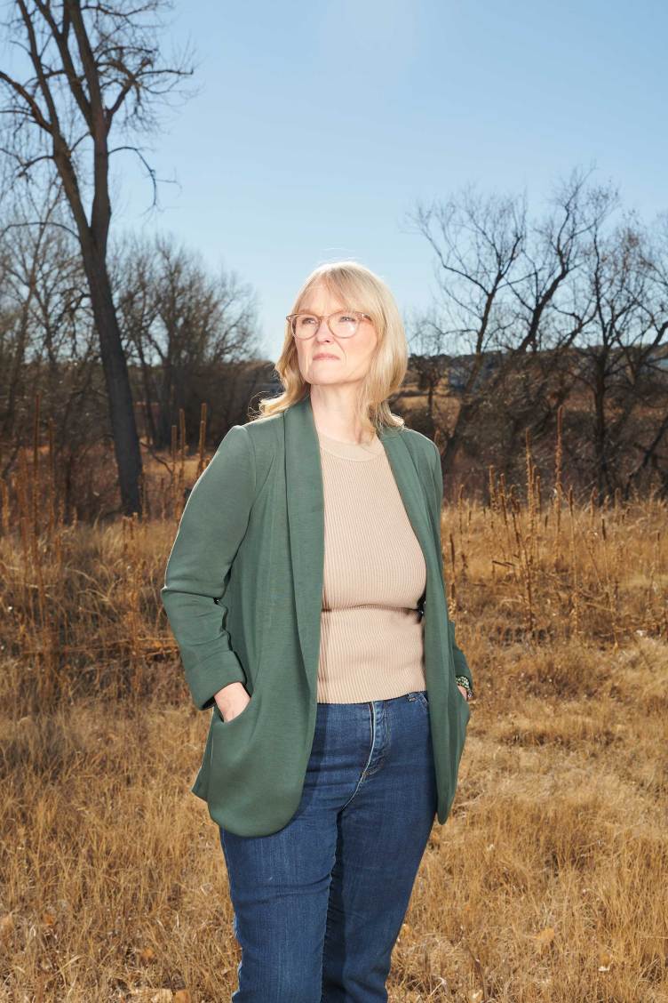 A woman with blond hair and glasses standing in a field.
