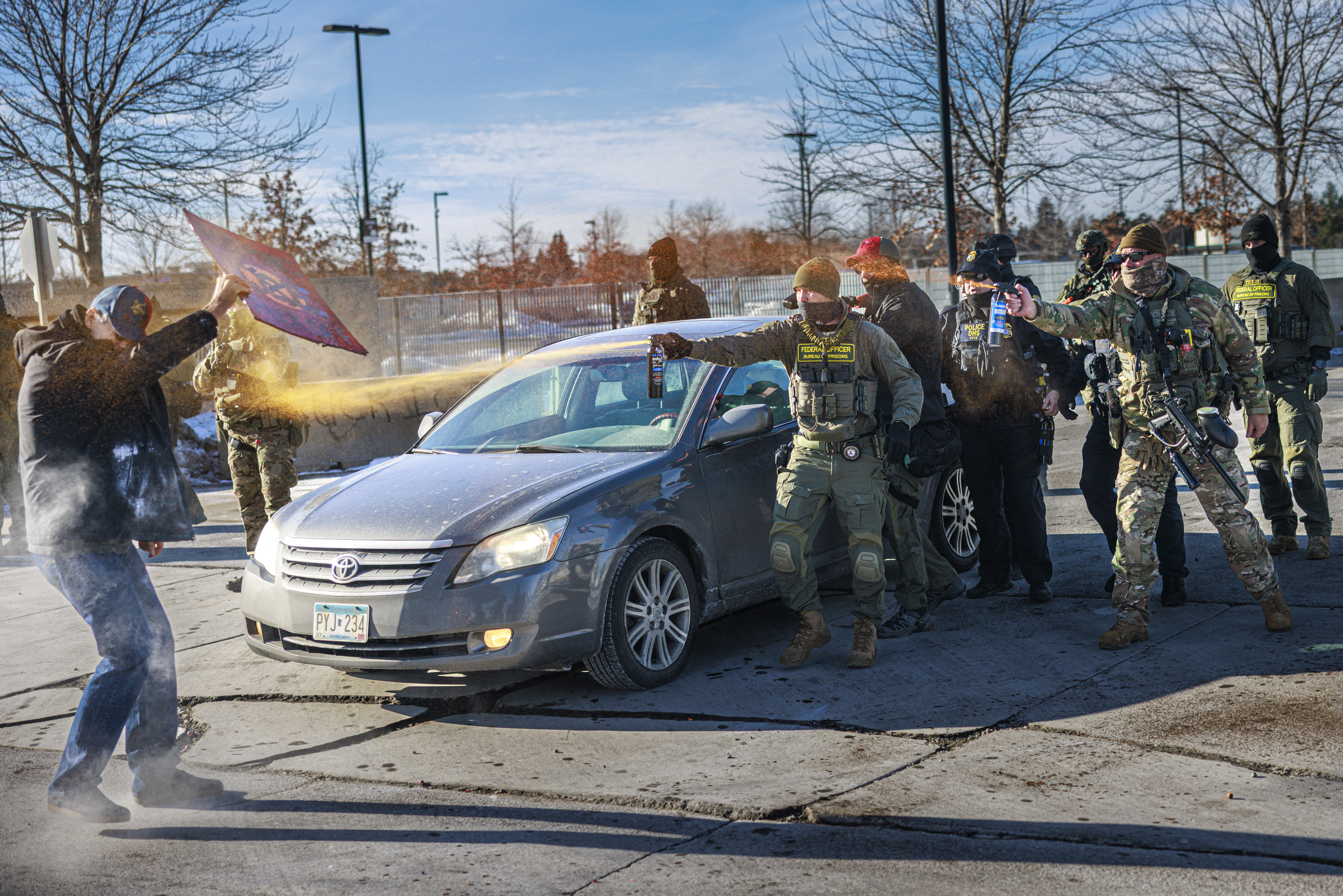 TOPSHOT - Federal agents use pepper spray against a protester holding a sign during an enforcement operation outside the Whipple Building, ICE facility in Minneapolis, Minnesota, on January 11, 2026. A US Immigration and Customs Enforcement (ICE) agent shot and killed 37-year-old Renee Nicole Good on the streets of Minneapolis on January 7, leading to huge protests and outrage from local leaders who rejected White House claims she was a domestic terrorist. (Photo by Kerem YUCEL / AFP via Getty Images)