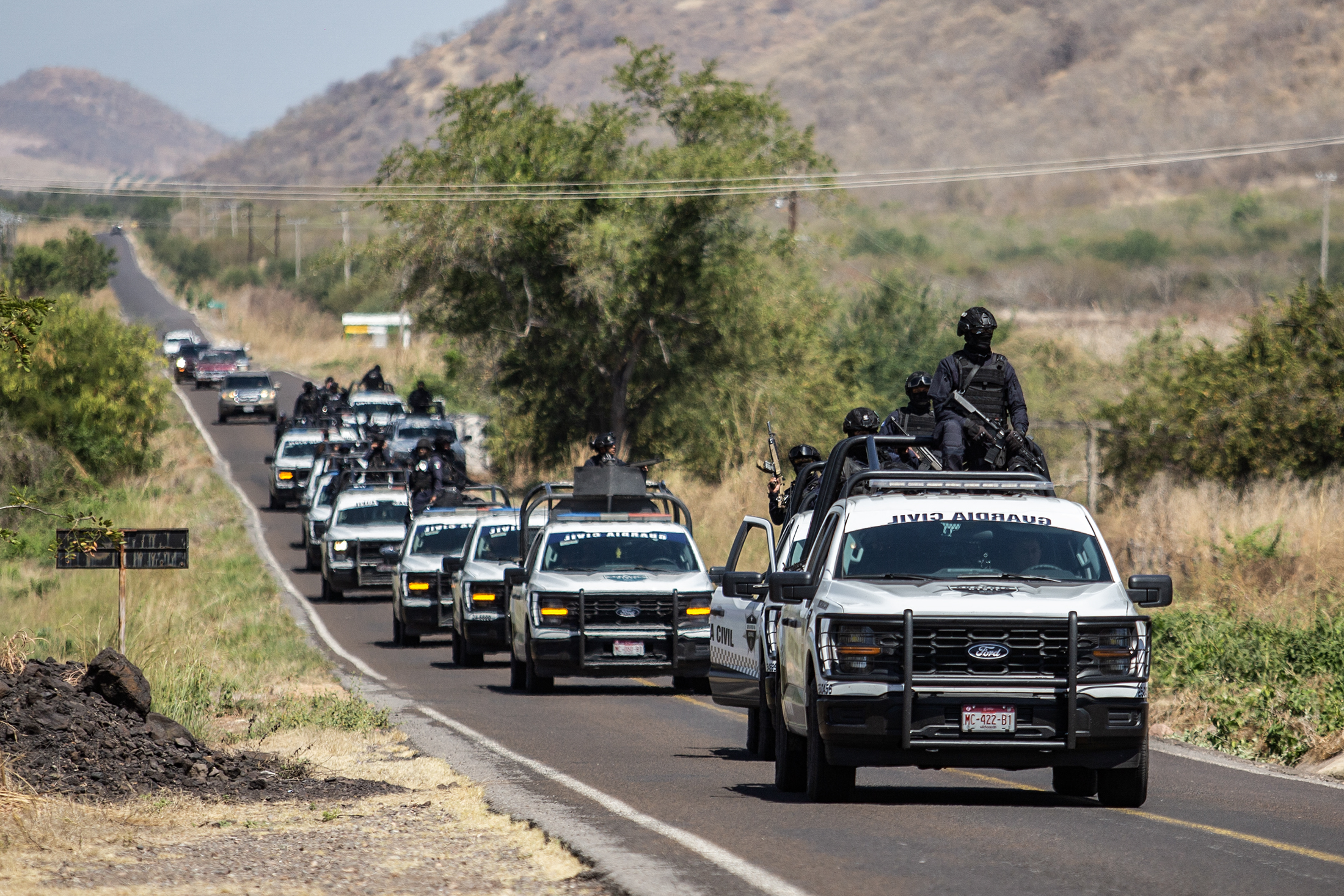 TOPSHOT - Members of the Civil Guard of Michoacan patrol a highway supported by armored vehicles after a wave of violence in the town of Aguililla, the birthplace of drug kingpin Nemesio Oseguera, leader of the Jalisco New Generation Cartel (CJNG) in Tierra Caliente, Mexico, on February 24, 2026. Mexican President Claudia Sheinbaum on February 24 dismissed risks to fans visiting Guadalajara, one of the venues for the 2026 World Cup, after a drug cartel riot caused fear in the city and much of the country on February 22. (Photo by Enrique Castro / AFP via Getty Images)