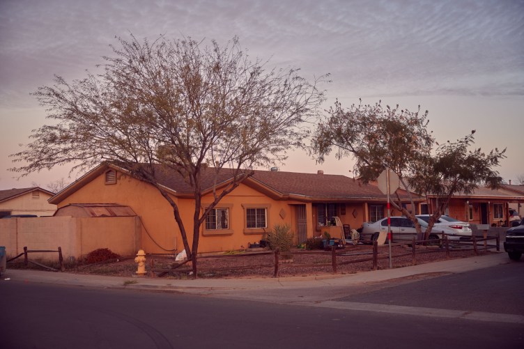 A yellowy orange house in a suburban neighborhood on a cloudy day.