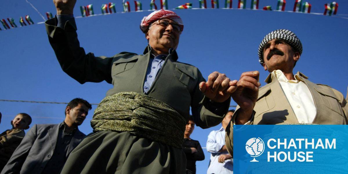 Iraqi Kurdish men dance in celebration, one holding a Kurdish flag