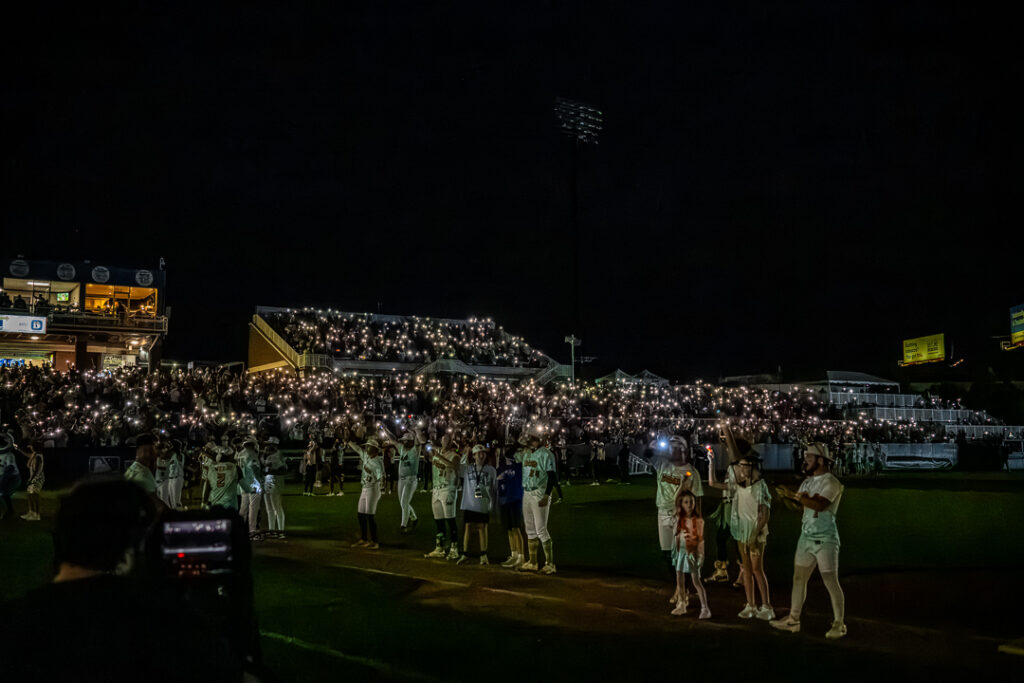 The stadium goes dark in the middle of the eighth as the teams and crowd sing along to "3 Little Birds" by Bob Marley.