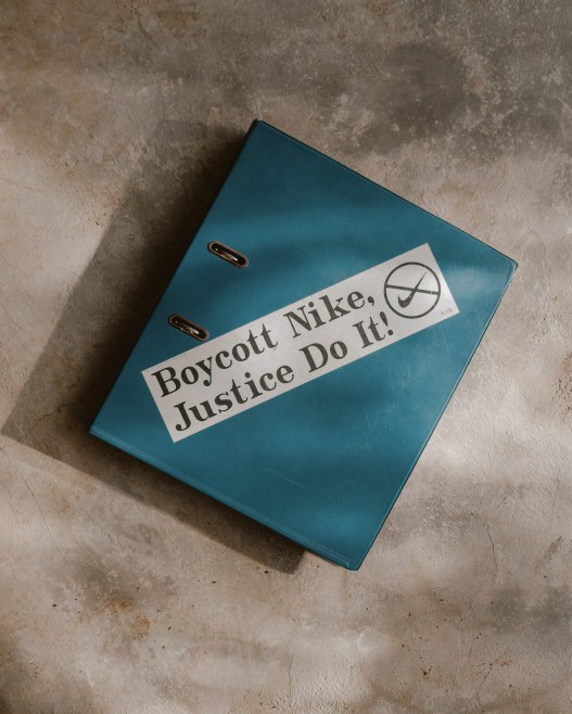 A teal binder with a sticker that says “Boycott Nike, Justice Do It!” with a crossed-out Nike swoosh logo.