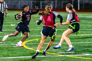 Caravel senior Amani Sudler tries to evade two Ursuline defenders in Caravel's girls flag football game against Ursuline.