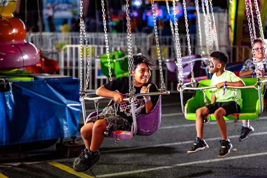 Young fairgoers return to the ground after swinging through the night sky.
