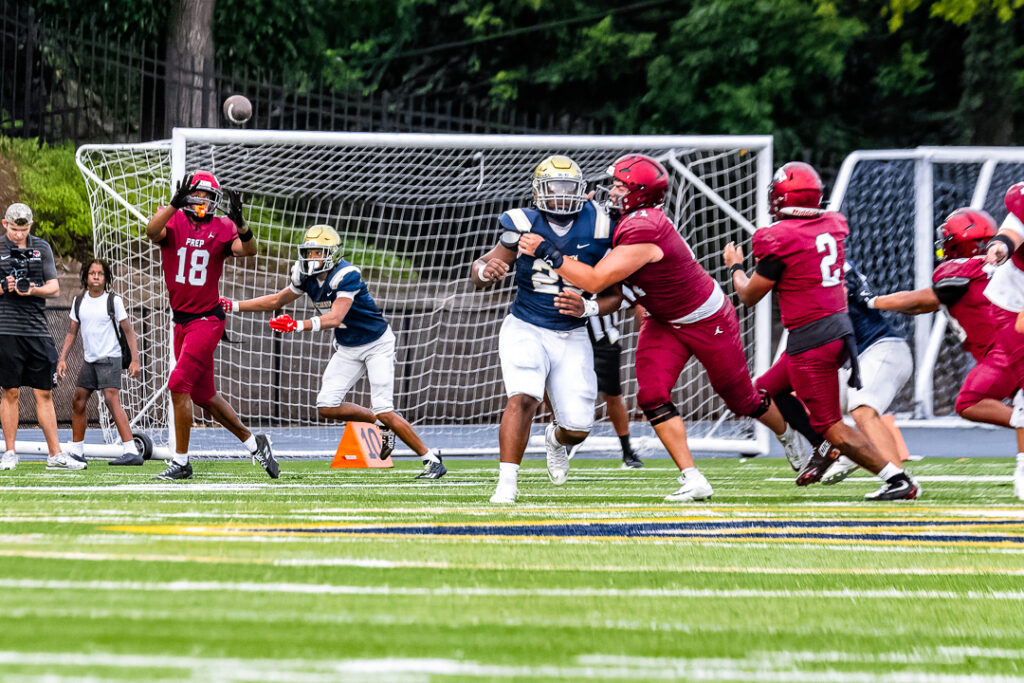 A Hawks receiver focuses on making the catch as a Sallies defender attempts to break it up.