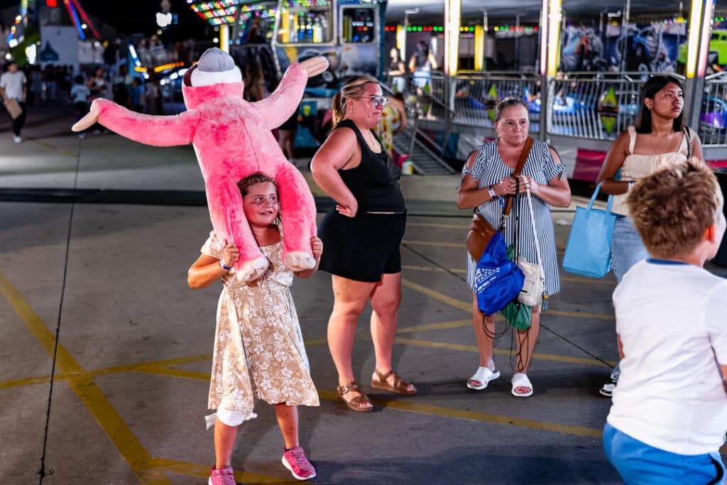 A little girl smiles with with her pink monkey on her shoulders after winning the prize at one of the Delaware State Fair game booths. 
