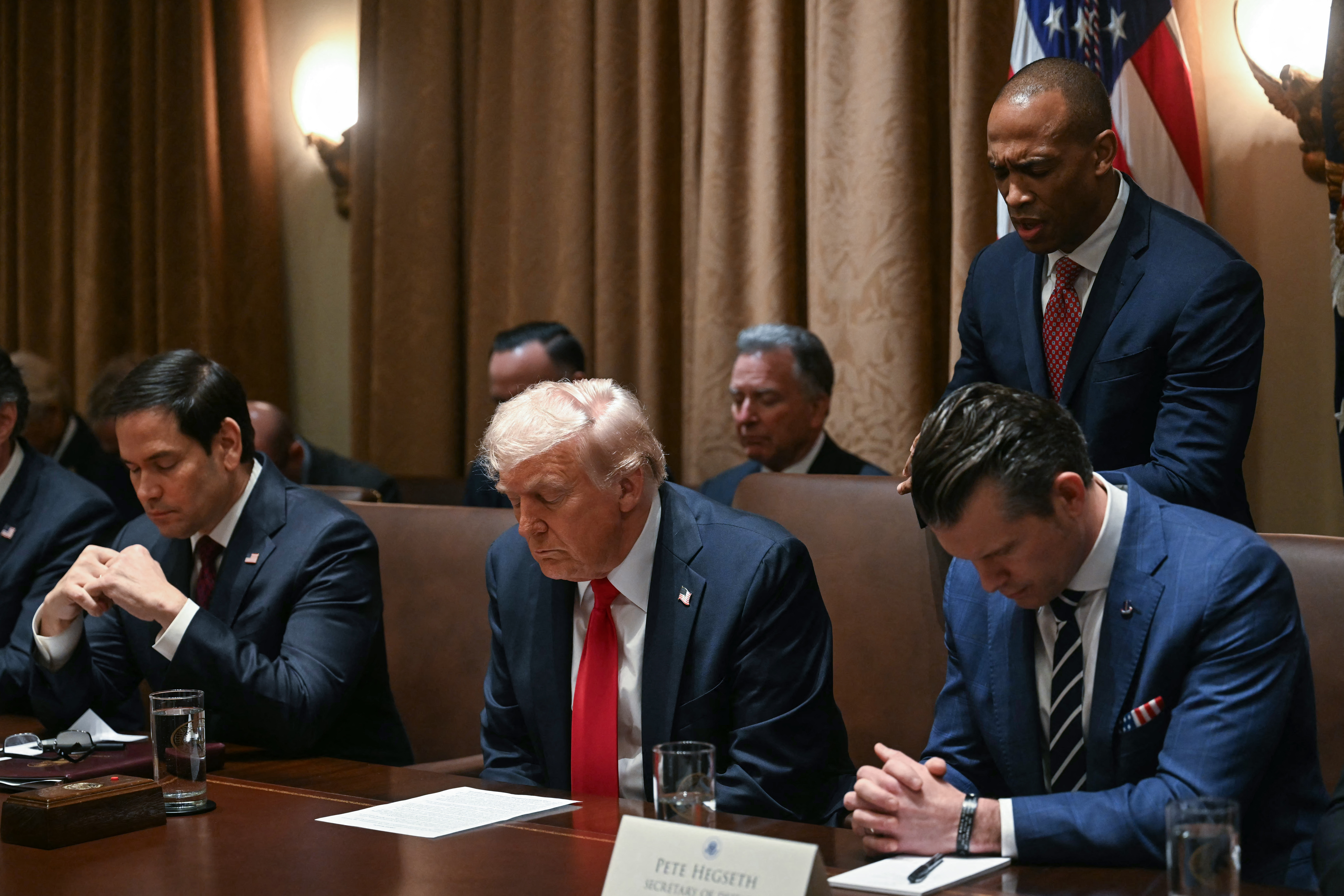 US President Donald Trump bows his head in prayer during a cabinet meeting at the White House in Washington, DC, on February 26, 2025. Also pictured, L-R, Secretary of State Marco Rubio, Secretary of Defense Pete Hegseth and House and Urban Development Secretary Scott Turner. (Photo by Jim WATSON / AFP) (Photo by JIM WATSON/AFP via Getty Images)