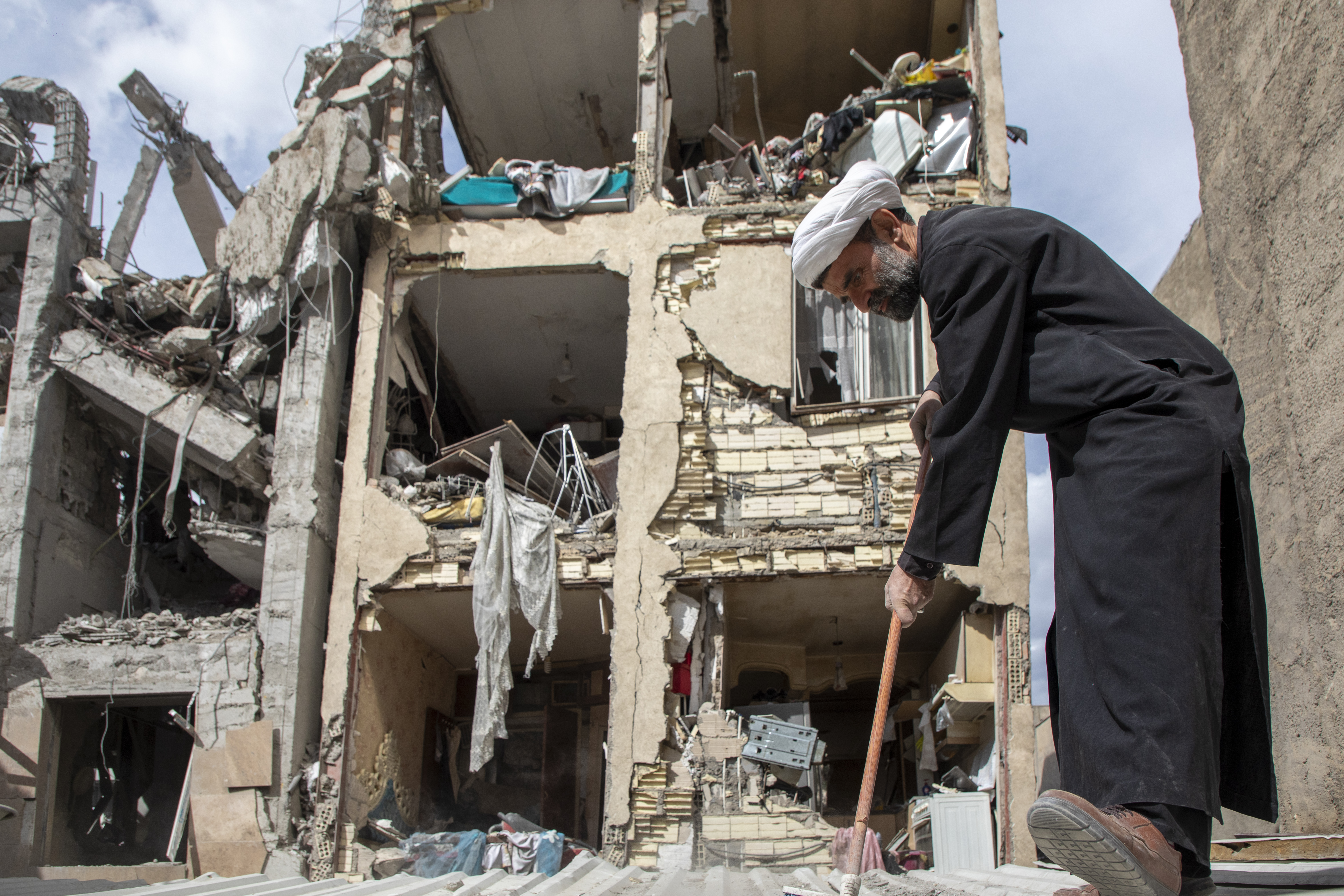 TEHRAN, IRAN - MARCH 27: A man sweeps up debris near a residential building that was hit in an airstrike in the early hours of March 27, 2026 in Tehran, Iran. The Israeli military said that it had carried out strikes on targets across Tehran and other Iranian cities overnight. The United States and Israel have continued their joint attack on Iran that began on February 28. Iran retaliated by firing waves of missiles and drones at Israel and U.S. allies in the region, while also effectively blockading the Strait of Hormuz, a critical shipping route. (Photo by Majid Saeedi/Getty Images)