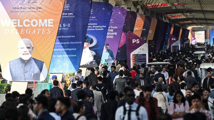 Visitors walk past a banner featuring India's Prime Minister Narendra Modi, as they arrive at the AI Impact Summit in New Delhi
