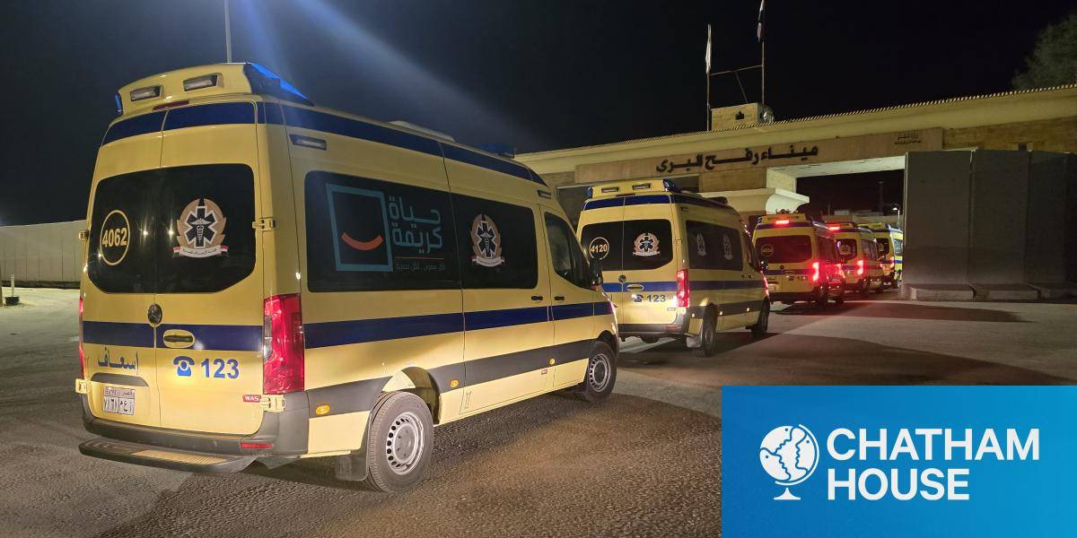 A queue of yellow ambulances entering the Gaza Strip via the Rafah Border Crossing at night