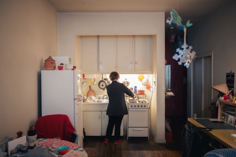 A white woman in her 70s makes a meal in her apartment.