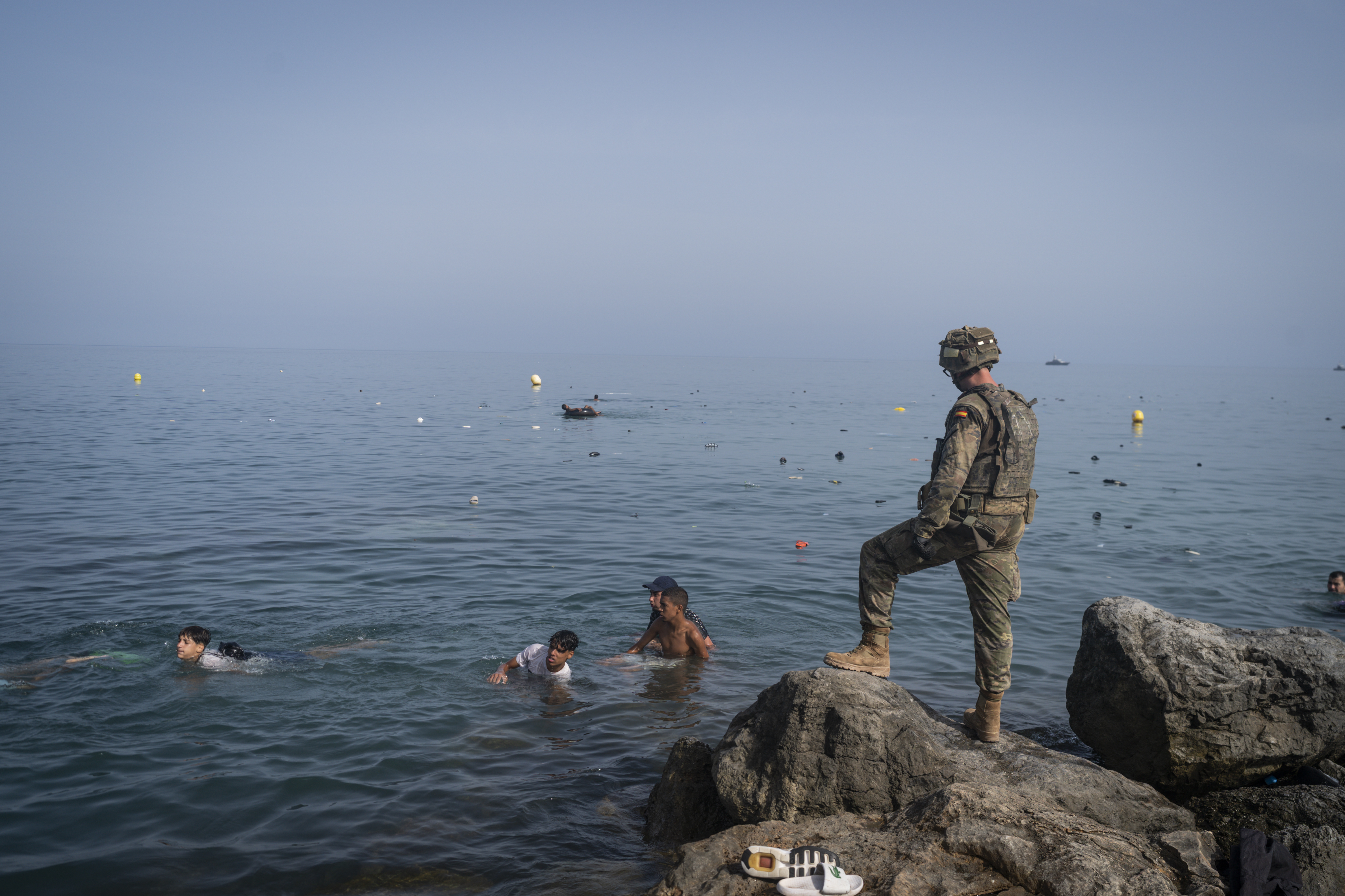 CEUTA, SPAIN - JULY 31: A member of the armed services watches over migrants crossing the border between Spain and Morocco on July 31, 2026 in Ceuta, Spain. Spain's interior ministry has said it's deploying 60 members of the armed forces and an additional 30 Guardia Civil officers to Ceuta after tens of thousands of migrants entered the Spanish enclave in North Africa on Thursday. A large number of people swam through the Tarajal breakwater to enter the Spanish territory from neighboring Morocco, while others scaled the border fence. Some estimates have said that around 49,000  migrants made the crossing, with the surge of arrivals overwhelming migrant reception centres, with many sleeping on the streets overnight. (Photo by Adri Salido/Getty Images)