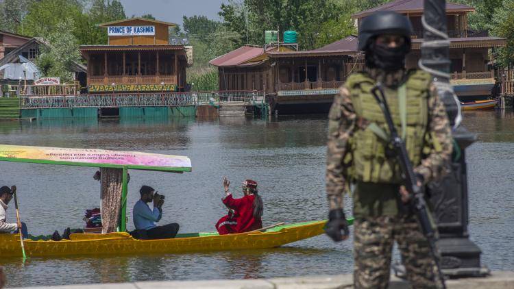 A local Kashmiri photographer take pictures of an Indian tourist in a boat as an Indian paramilitary soldier stands guard on the bank of Dal lake.