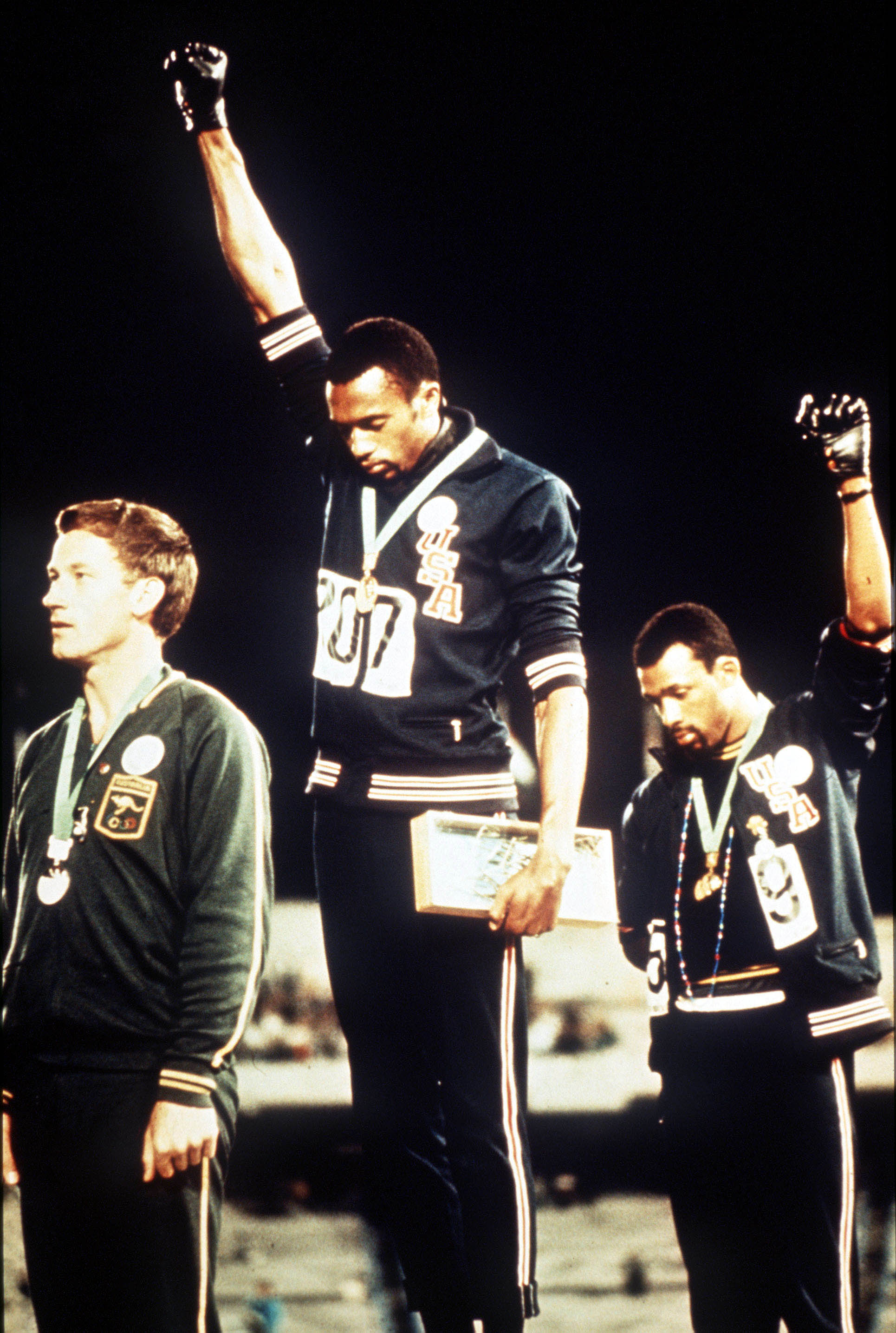 The medal presentation for the Men’s 200 metres final at the 1968 Summer Olympics, American athletes, gold medalist Tommie Smith (in centre) and bronze medalist John Carlos (right) each raise a clenched fist and bow their heads during the United States National Anthem, as a Human Rights protest, while they stand on the podium with Australian silver medalist Peter Norman (1942-2006), in the Estadio Olimpico Universitario in Mexico City, Mexico on 16th October 1968. All three men wore badges expressing support for the Olympic Project for Human Rights; and Smith and Carlos' gestures have been described (by the men themselves) as both Black Power and Human Rights salutes. (Photo by Rolls Press/Popperfoto via Getty Images)