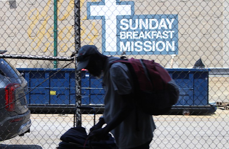 A man stands with his personal belongings outside the Sunday Breakfast Mission, a homeless shelter and service center in Wilmington, Delaware, in May 2024.