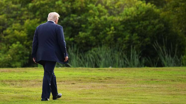 President Donald Trump walks alone to a helicopter