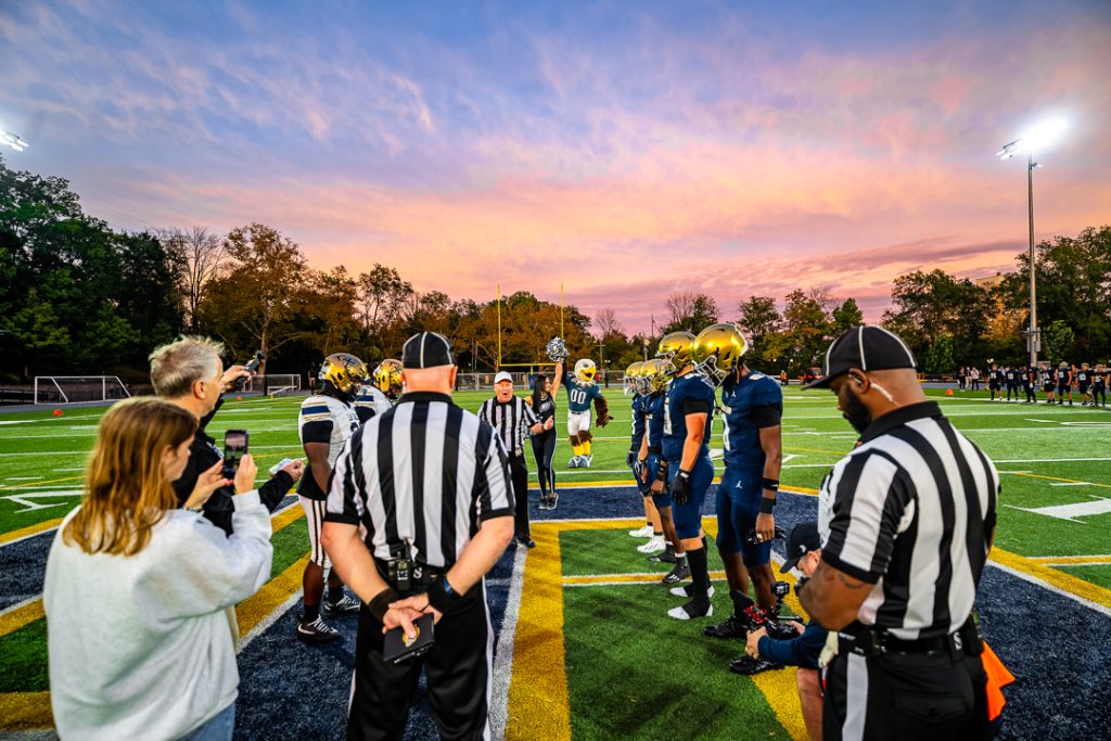The teams go through the coin toss with Swoop and the Eagles cheerleaders in the background. As a part of the Friday Night Captains program, the Eagles will make a donation to both football programs.