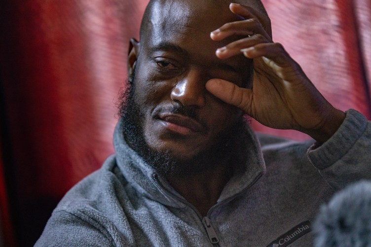A close-up photograph of a man wiping a tear from his eyes.