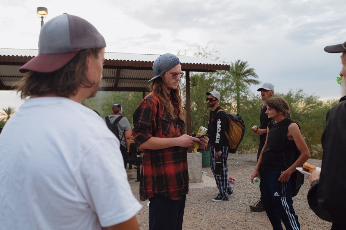 A group of people converse outdoors in a park at dusk.