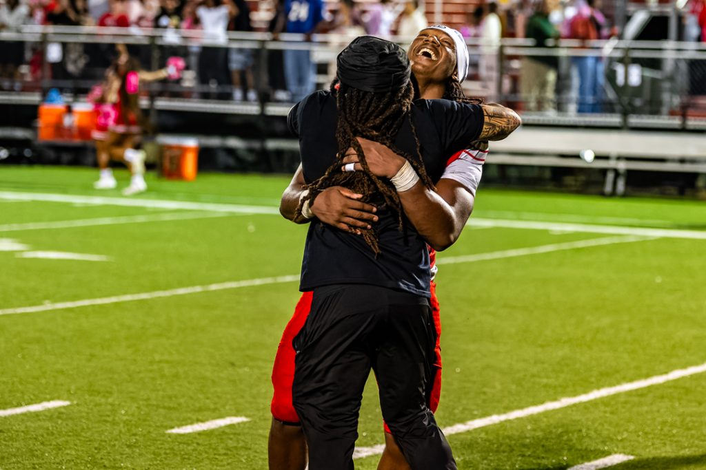 Ingram and assistant coach Marquis Johnson hug it out after the sophomore runner carried the ball over 20 times in the game.