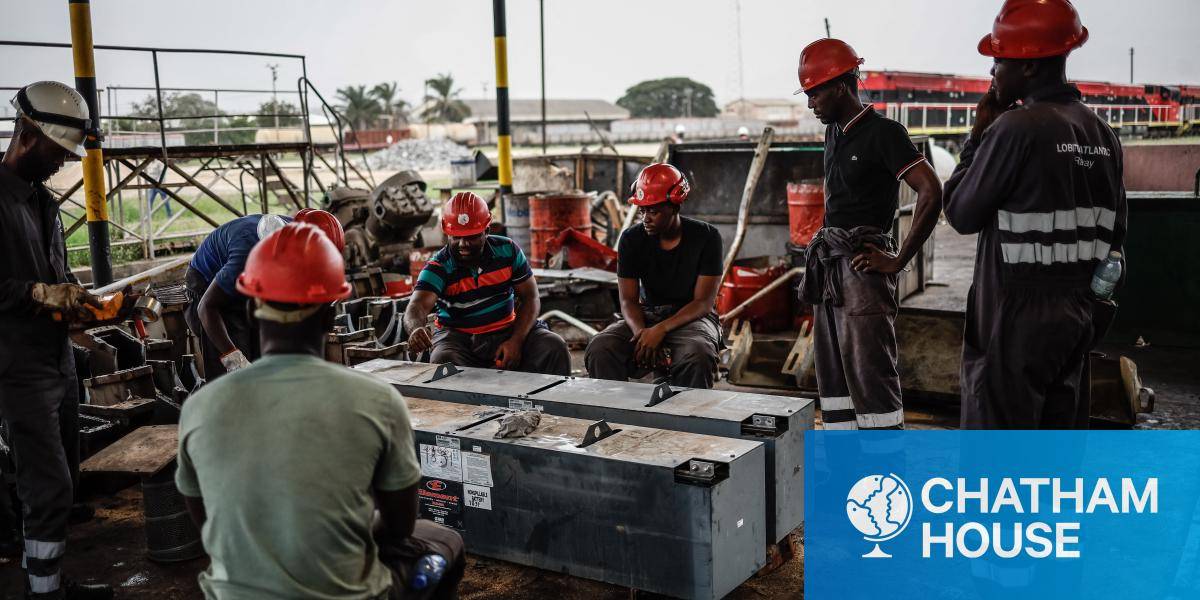 Workers carry out maintenance on a freight train battery in Lobito
