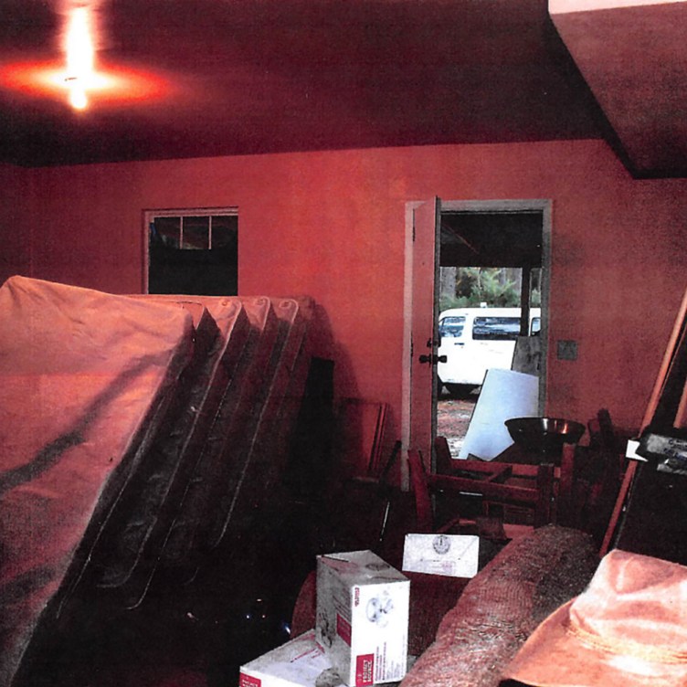 A dimly lit red room filled with mattresses stacked vertically.