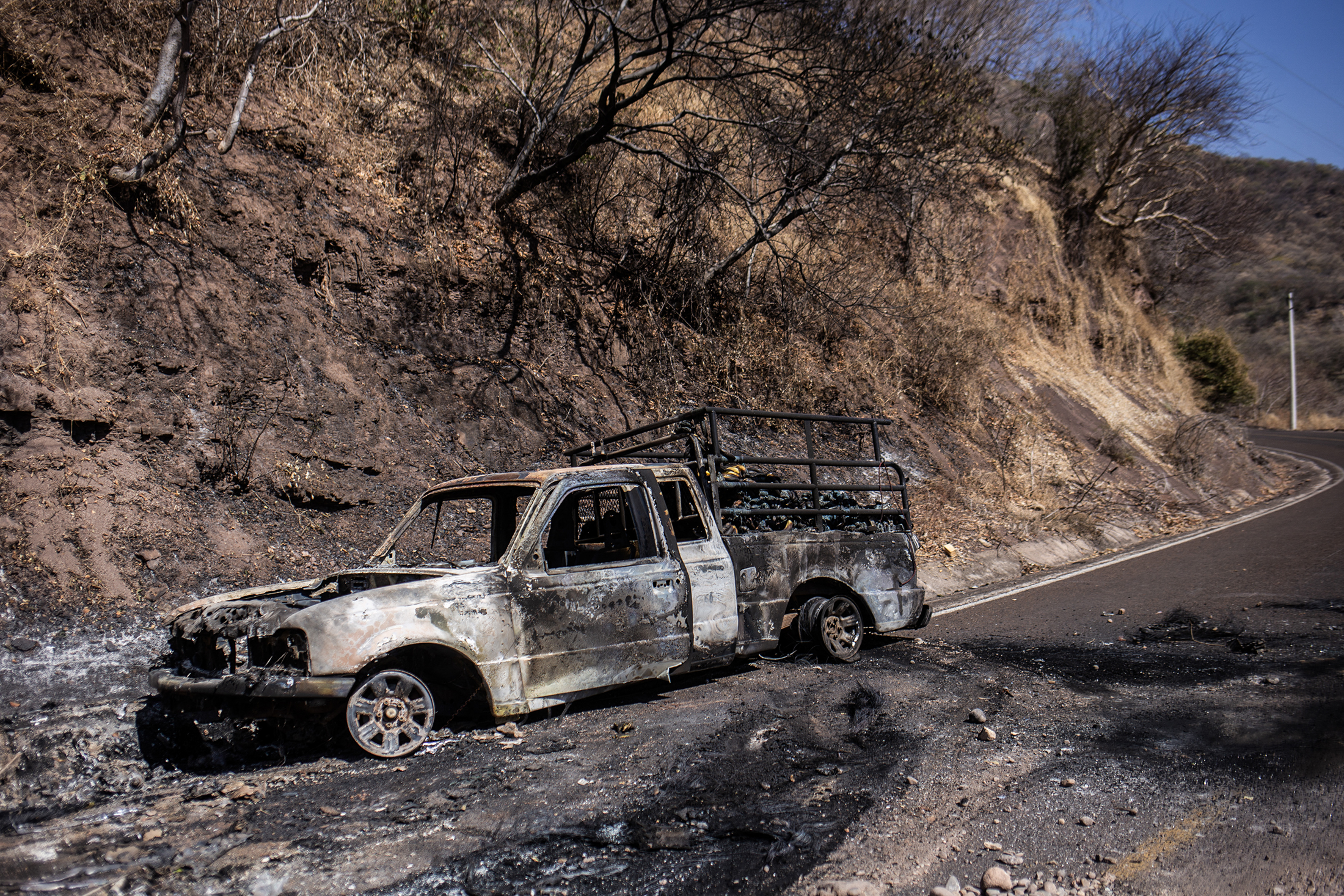 A burnt truck is pictured after a wave of violence in the town of Aguililla, the birthplace of drug kingpin Nemesio Oseguera, leader of the Jalisco New Generation Cartel (CJNG) in Tierra Caliente, Mexico, on February 24, 2026. Mexican President Claudia Sheinbaum on February 24 dismissed risks to fans visiting Guadalajara, one of the venues for the 2026 World Cup, after a drug cartel riot caused fear in the city and much of the country on February 22. (Photo by Enrique Castro / AFP via Getty Images)