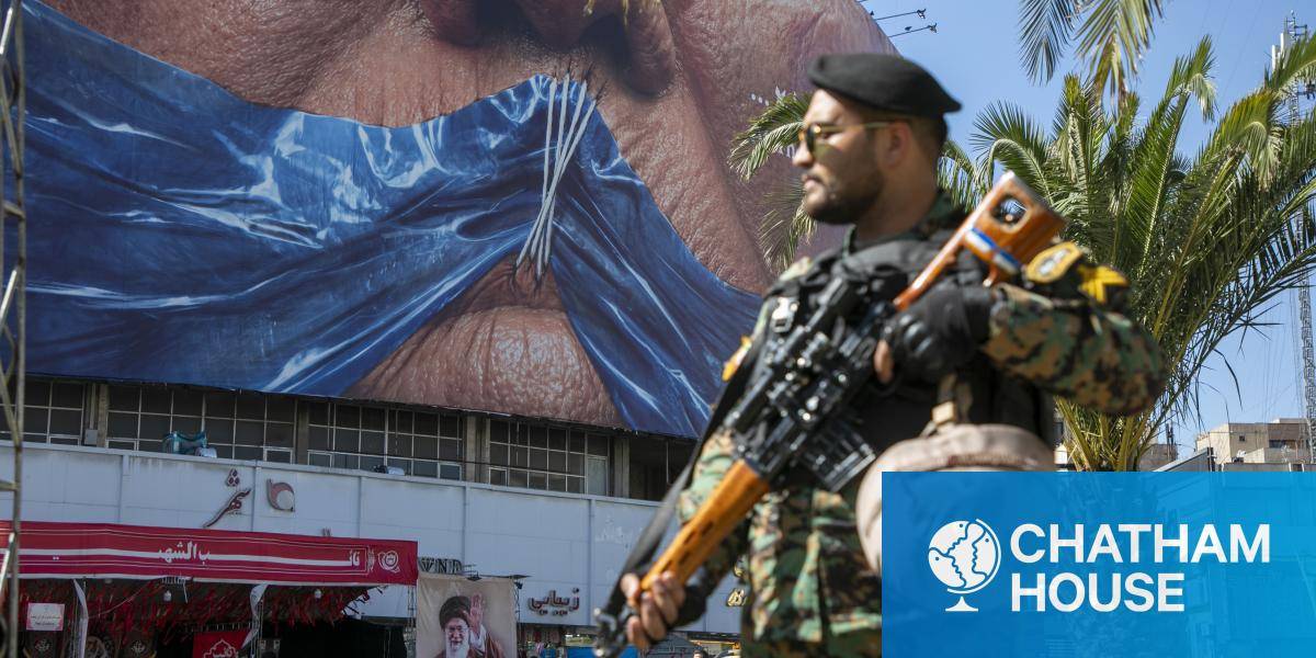 An Iranian police officer stands before a poster in Tehran, depicting President Trump's mouth gagged by a Strait of Hormuz shaped ribbon - May 2026.