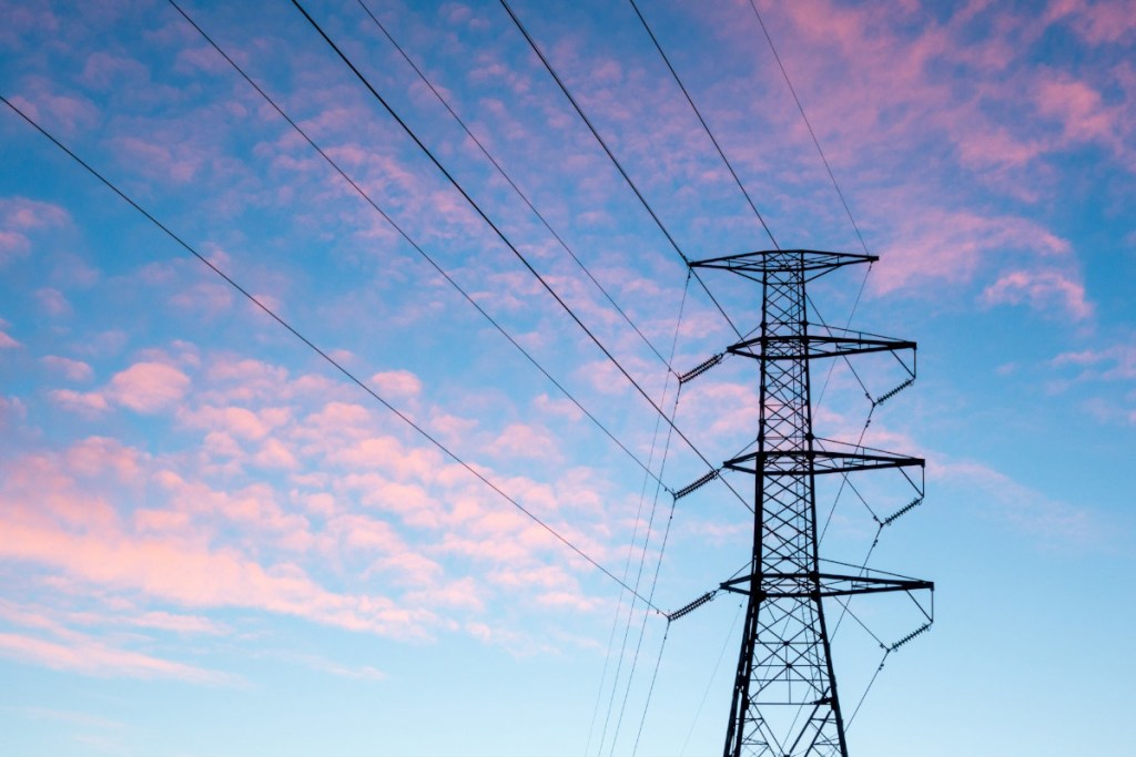 An electric transmission tower is seen against a dramatic sky.