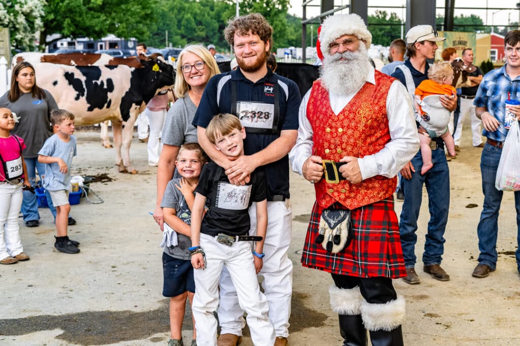 Contestants from the Open Dairy Cattle Show stop for a picture with Santa whose rocking a kilt to beat the summer heat.