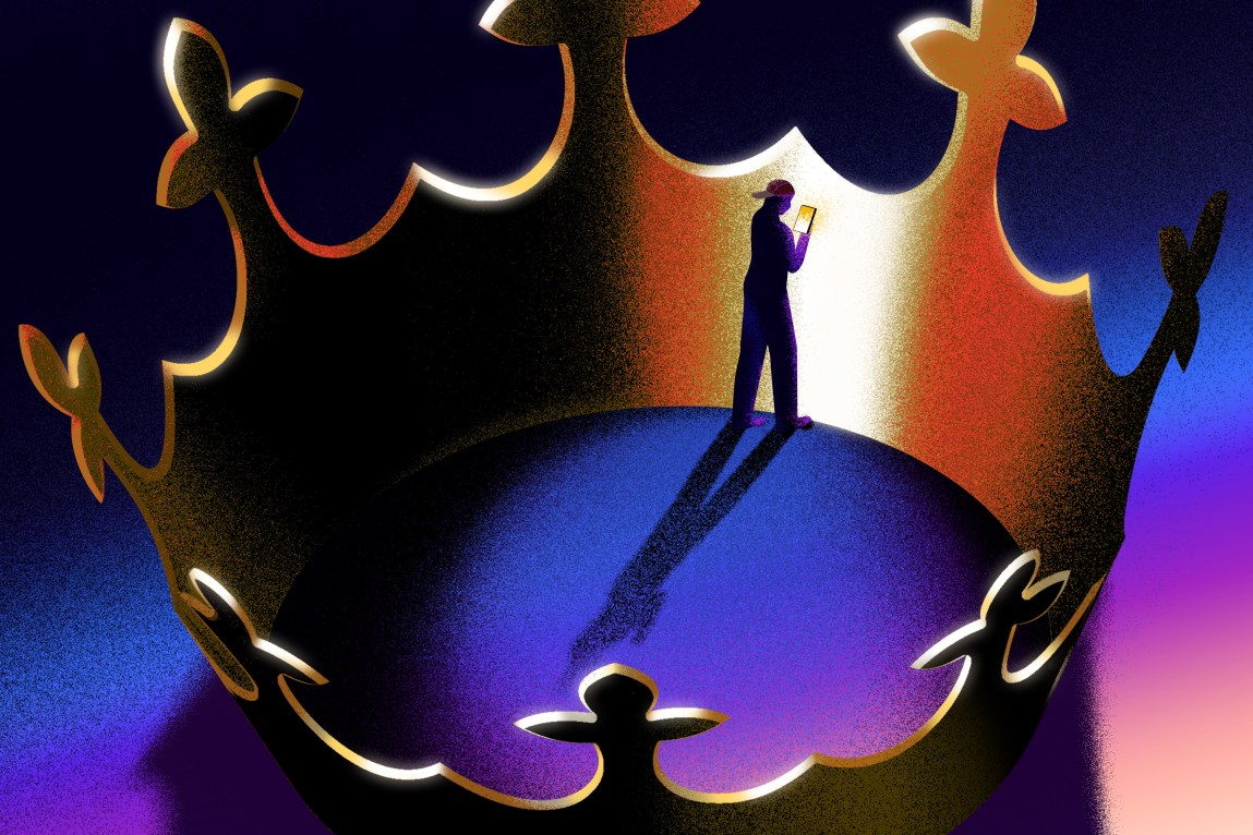 A large golden crown entraps a person wearing a baseball cap looking at a glowing smartphone.