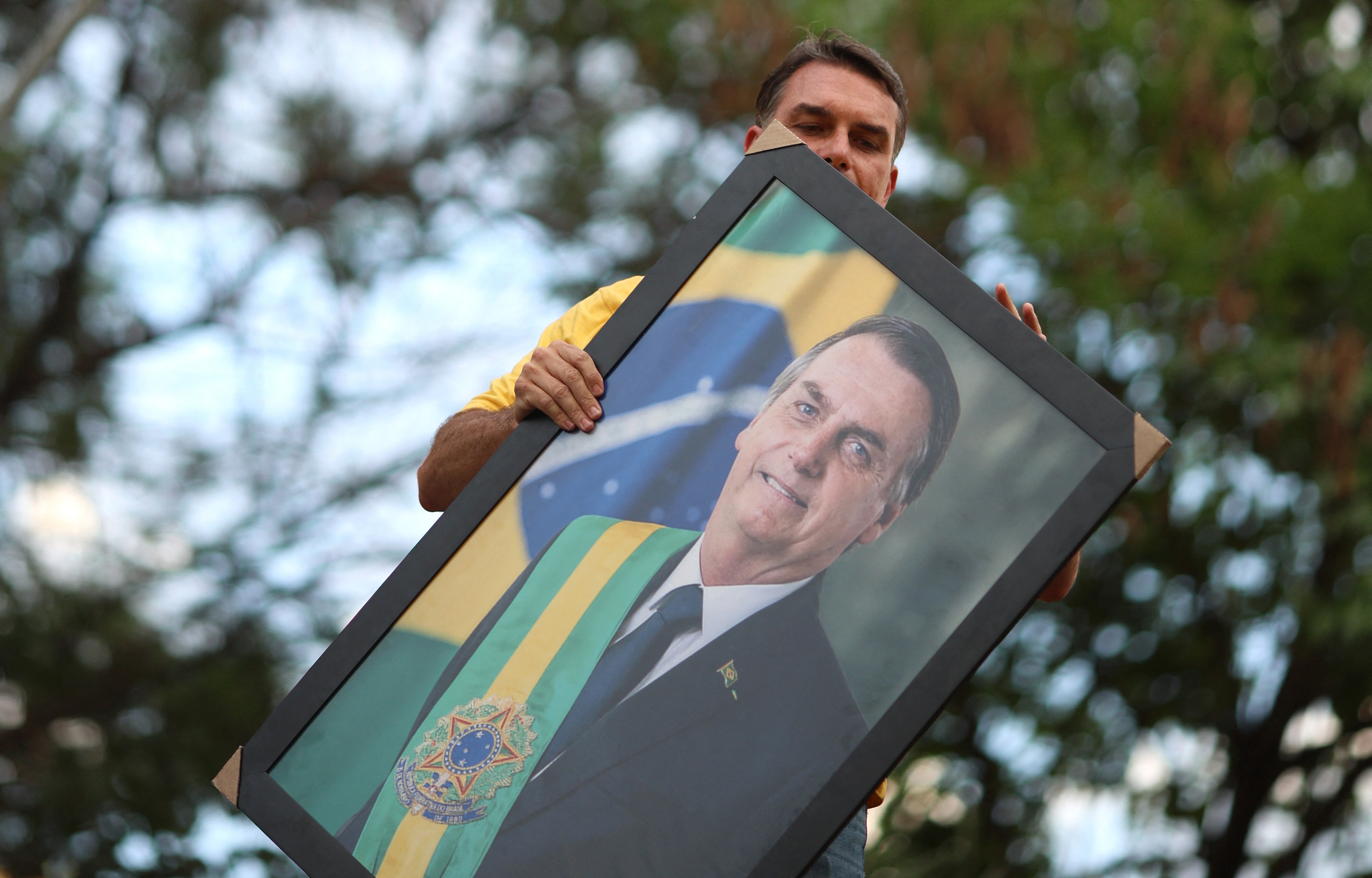 Brazilian right-wing presidential candidate Flavio Bolsonaro holds a picture of his father, convicted former President Jair Bolsonaro, during a motorcade with supporters in Goiania, Brazil, on September 27, 2026. Brazil will hold presidential election on October 4, 2026. (Photo by Sergio Lima / AFP via Getty Images)