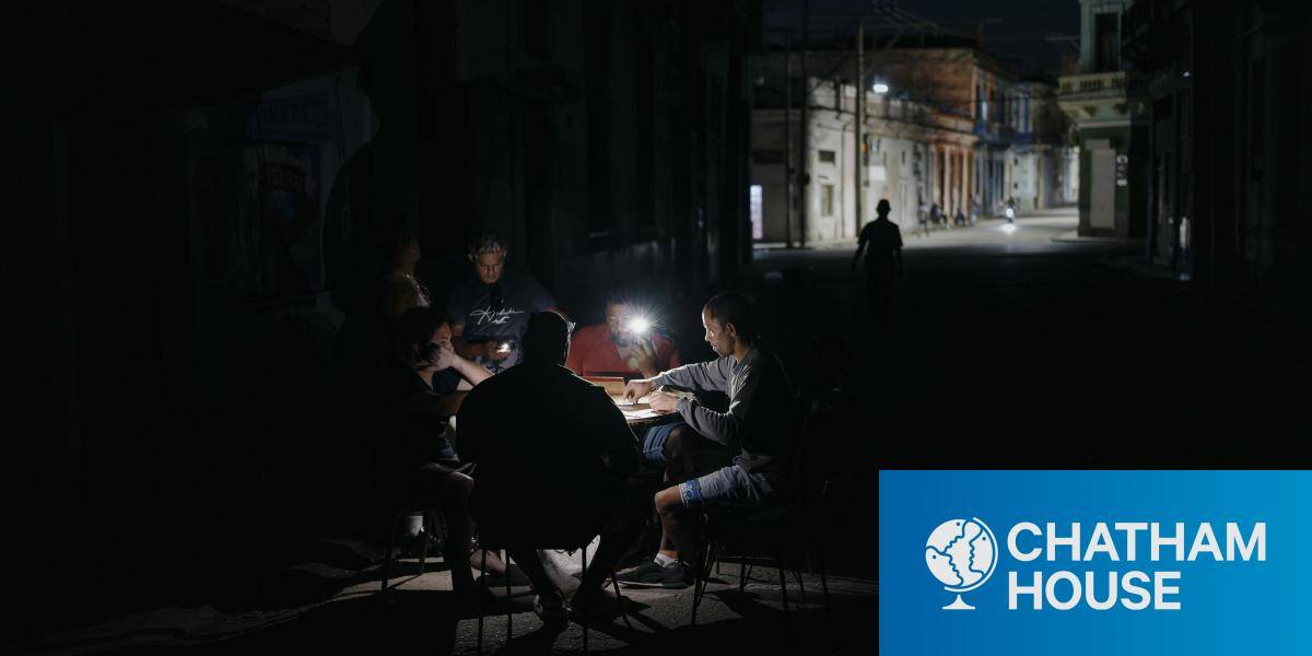 Men sit in dark street playing card with headtorches on