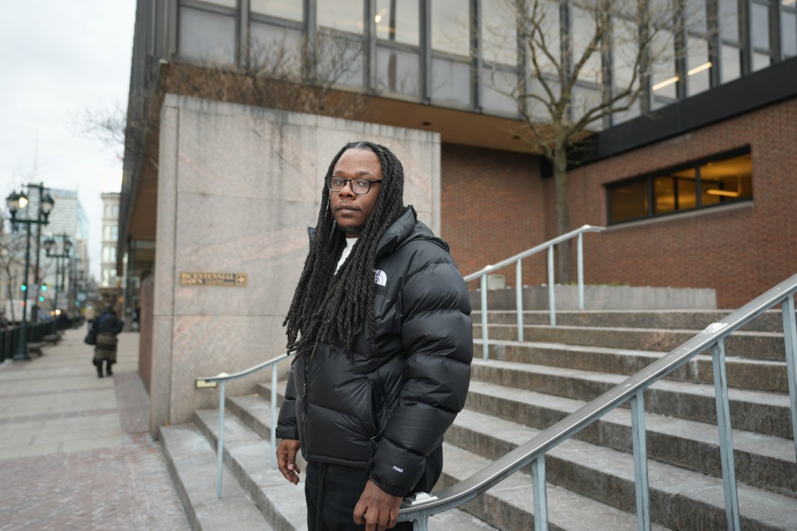 A man stands on steps outside a government building and looks at the camera.