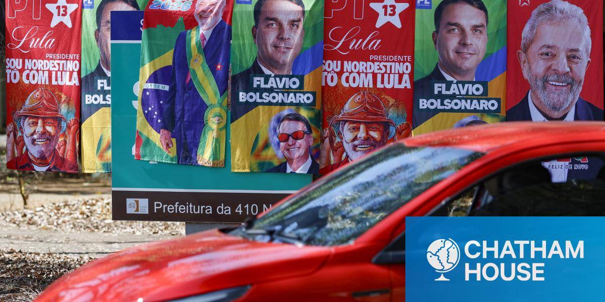 A car drives by a colourful display of election posters featuring presidential candidates Lula and Flavio Bolsonaro in Brasília. 