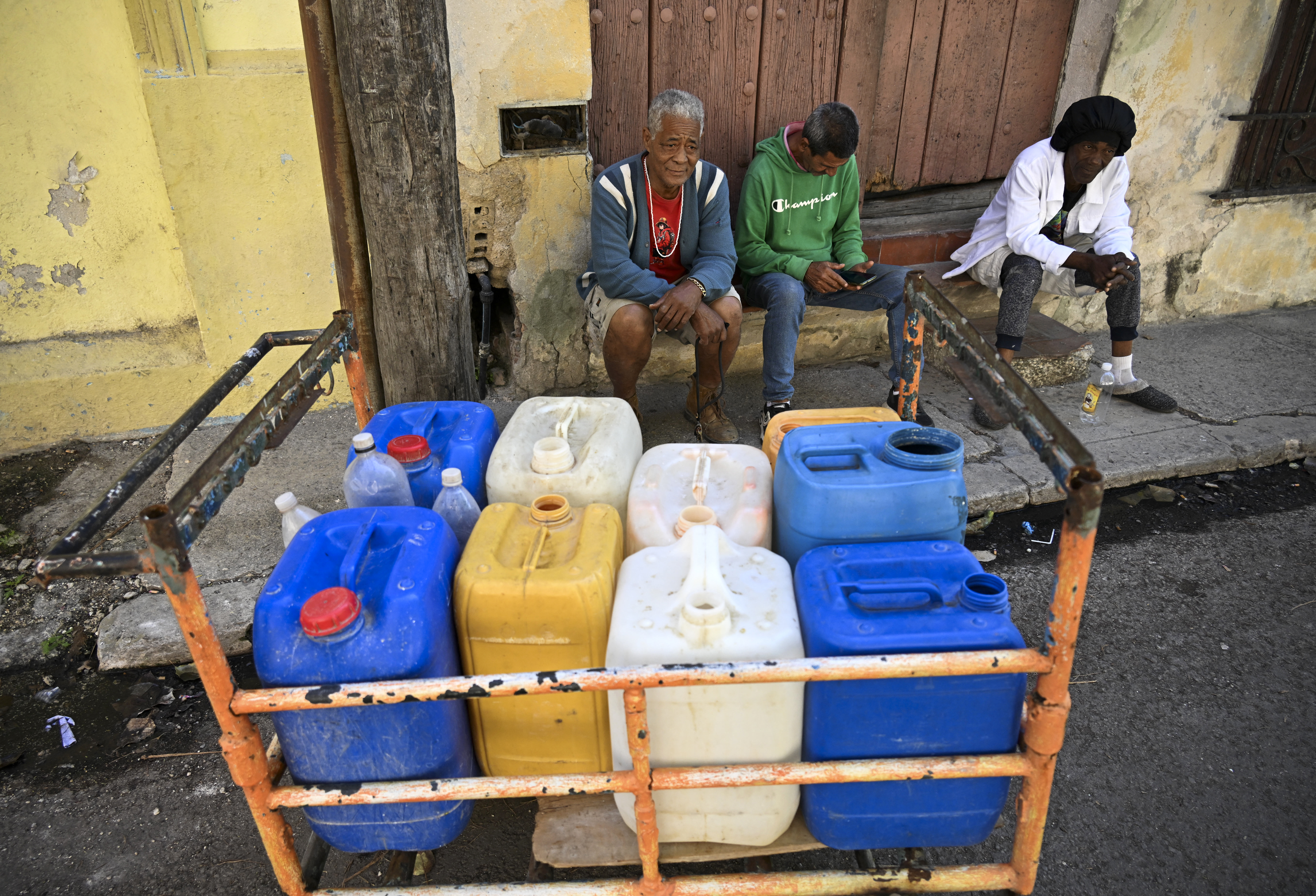 People queue to fill their water containers in Havana during a nationwide blackout on March 22, 2026. Cuban authorities scrambled on March 22 to restore power to the island after the second nationwide blackout in less than a week, as the grid struggles due to an aging infrastructure and a US oil blockade. (Photo by YAMIL LAGE / AFP via Getty Images)