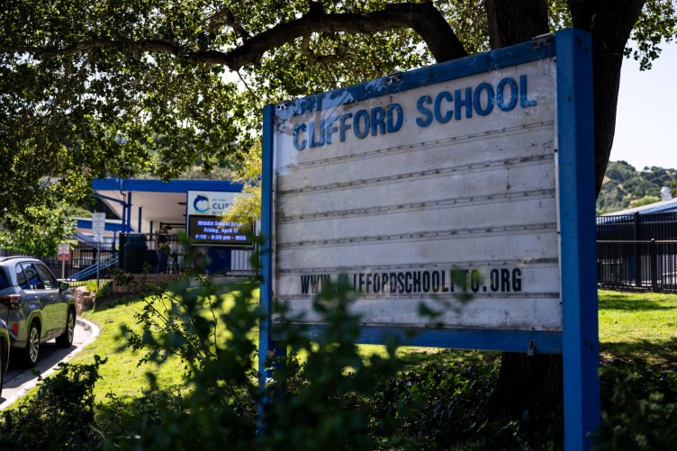 A school building with a sign in front of it that reads, “Clifford School.”