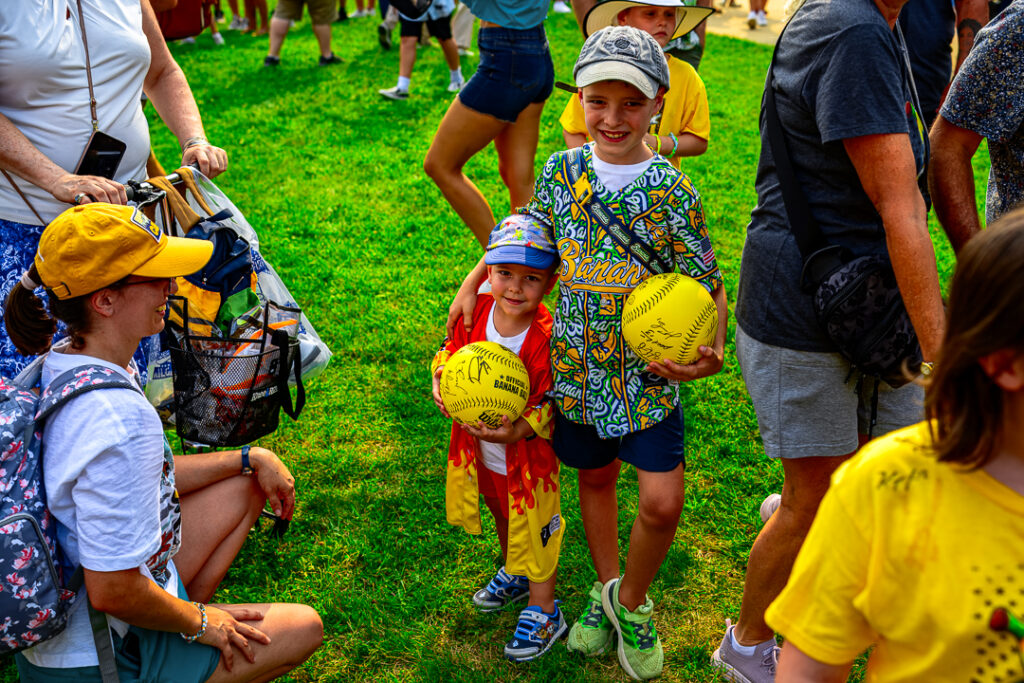 A couple young Banana Ball fans pose for a picture with their signed yellow baseballs. Players from both teams spent over an hour in the plaza signing autographs before the game.
