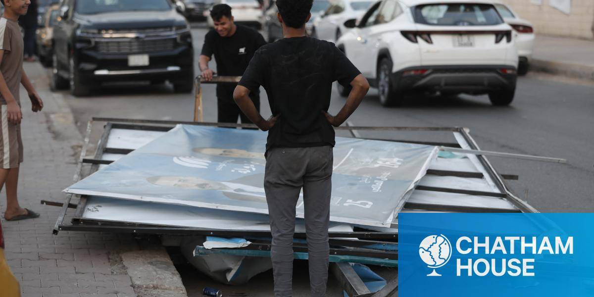 Young men remove electoral campaign posters after the closing of the polls during the Iraq's parliamentary election.