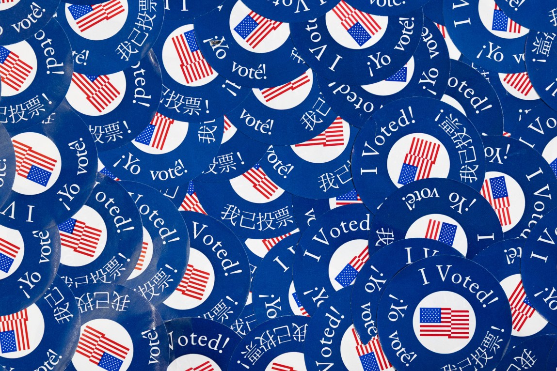 Blue circular stickers with an American flag and the words “I Voted!” in three languages.