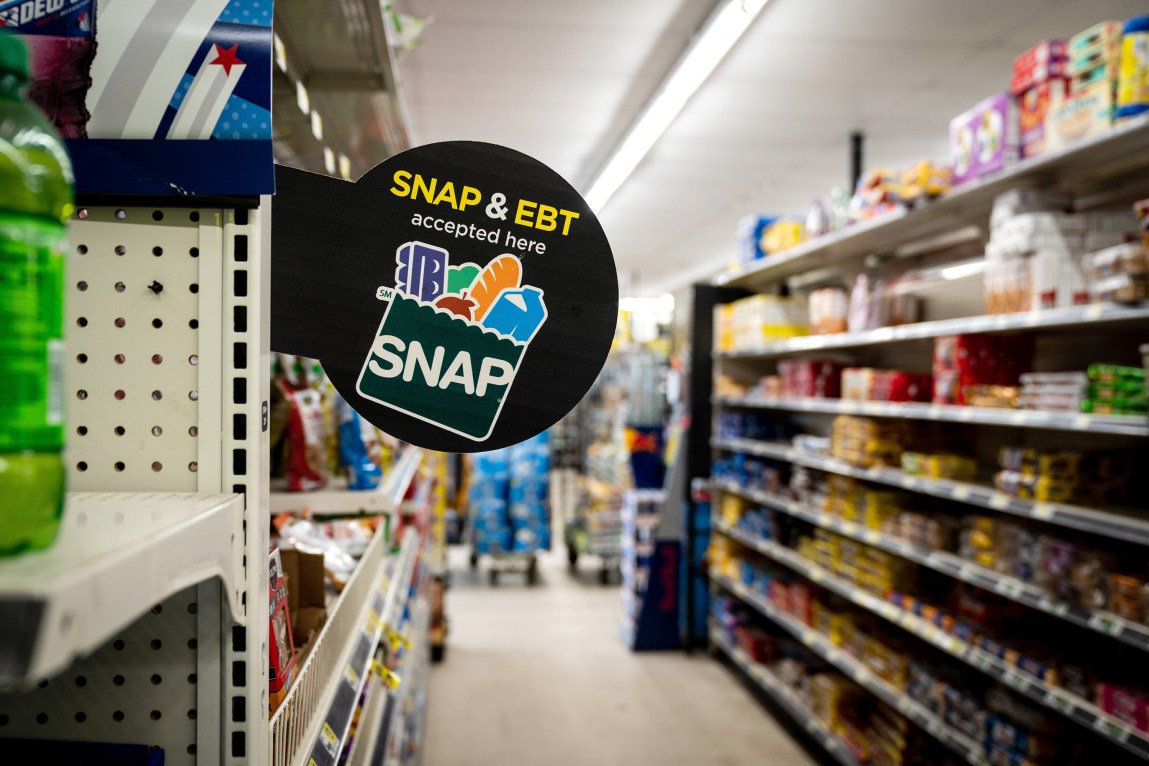 A sign that says “Snap and EBT accepted here” is displayed in the aisle of a grocery store.