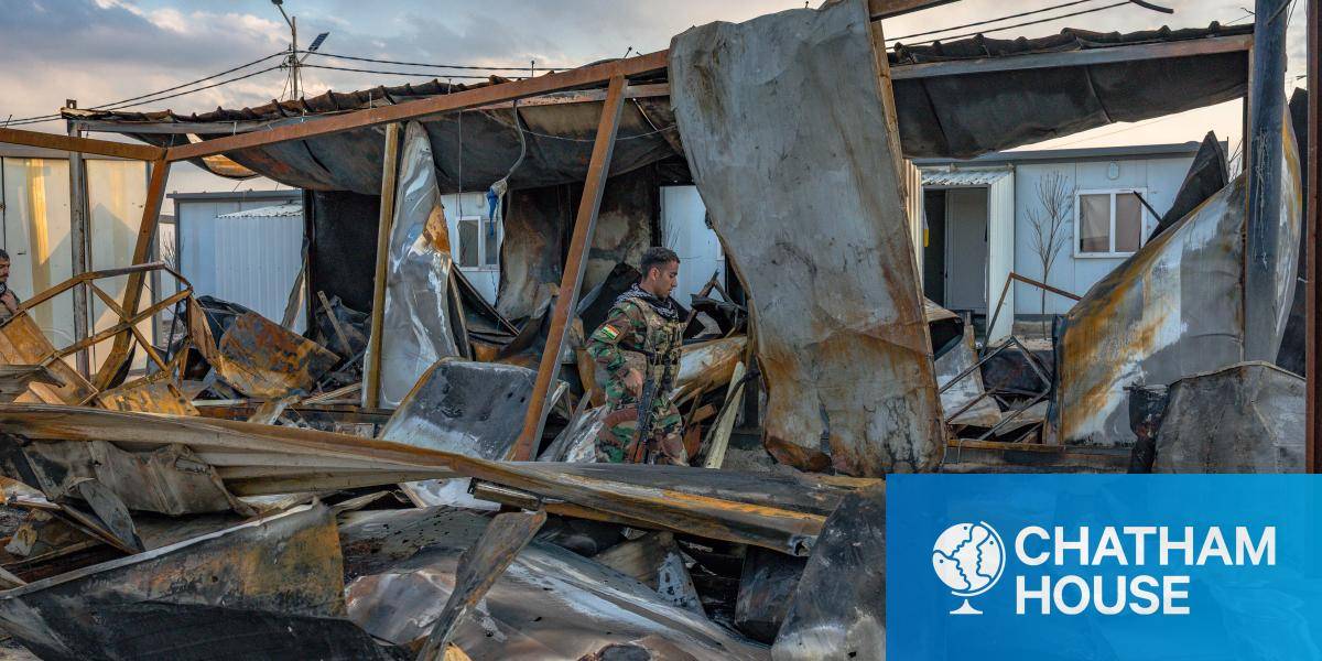 Kurdish fighters walk on the site of the outskirts of an Iranian Kurdish military facility north of Erbil after it was struck by an Iranian drone.