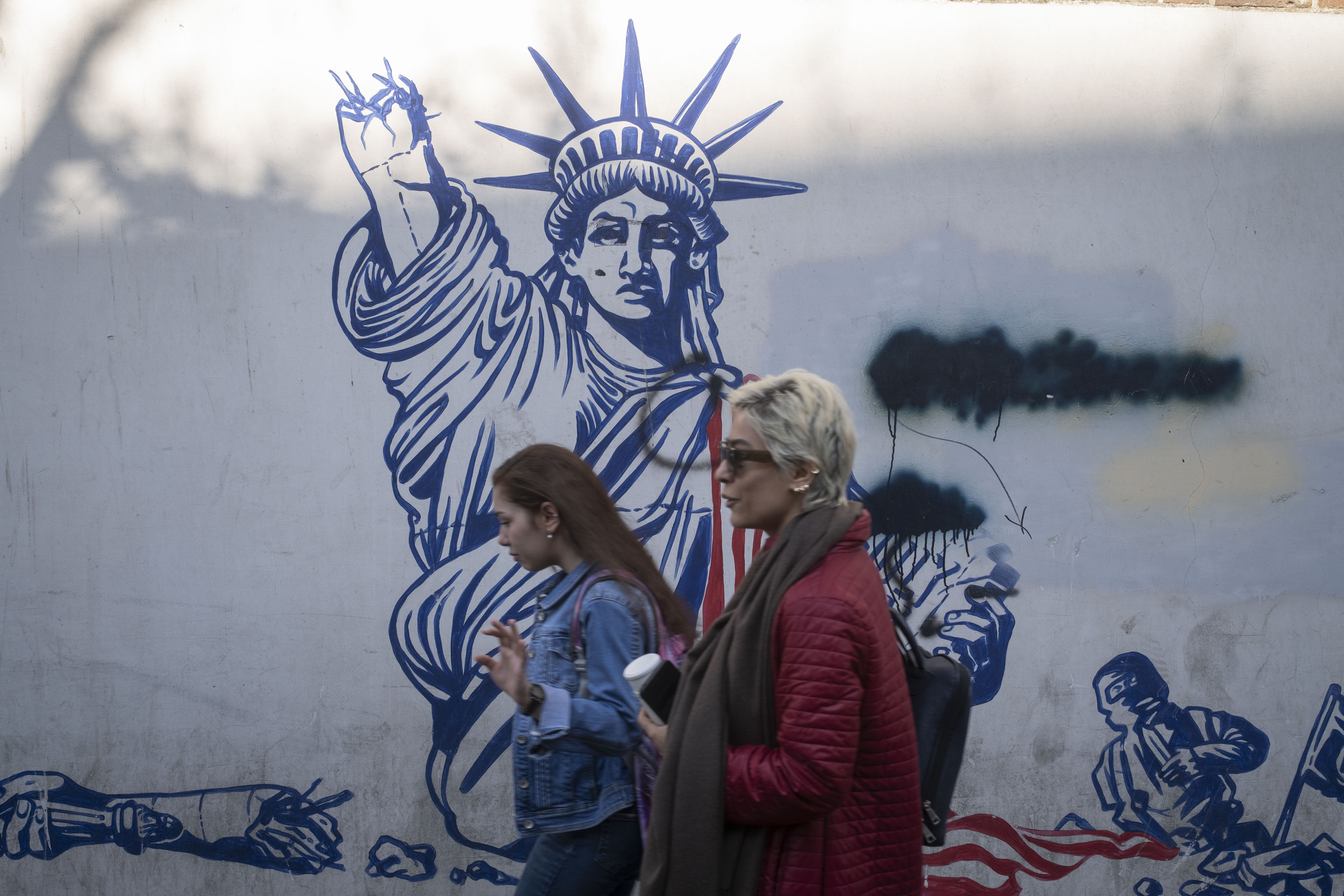 Two Iranian women walk past an anti-U.S. mural on the wall of the former U.S. embassy in downtown Tehran, Iran, on February 26, 2026, the final day of Iran-U.S. talks that are currently held in the city of Geneva. (Photo by Morteza Nikoubazl/NurPhoto via Getty Images)