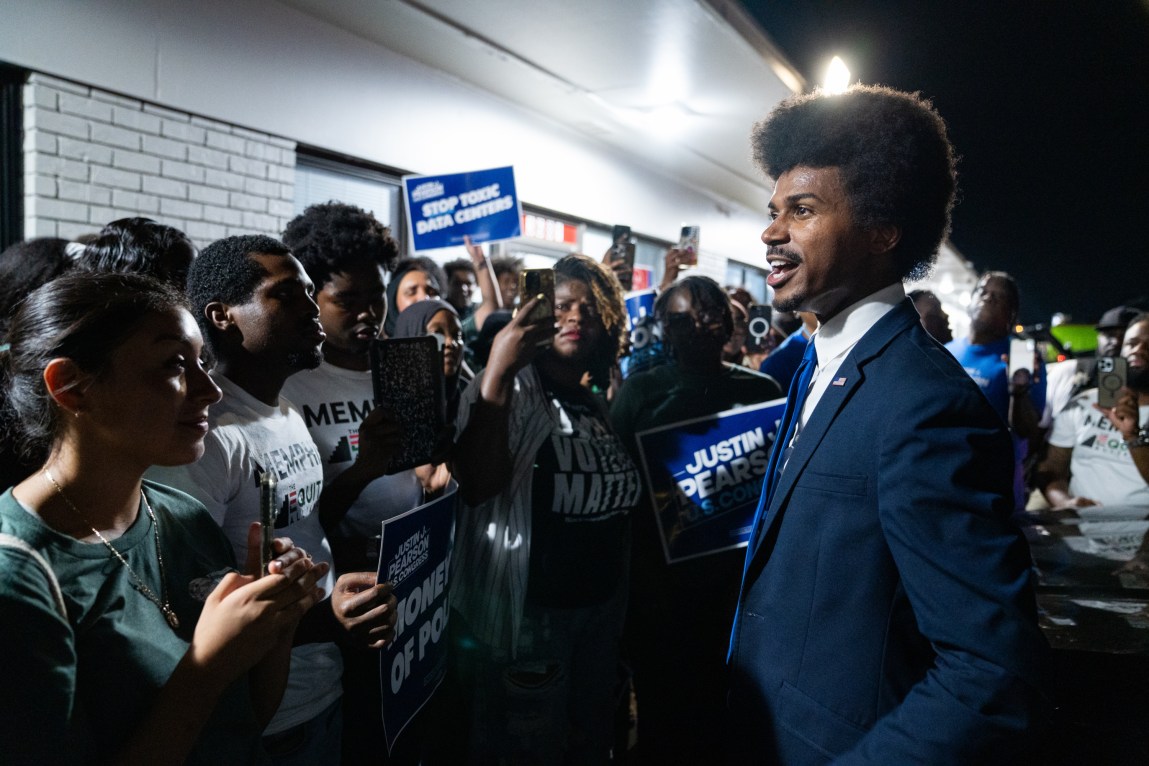A man wearing a suit speaks to a crowd of people who are holding signs that say, “Justin Pearson” and “Stop Toxic Data Centers.”