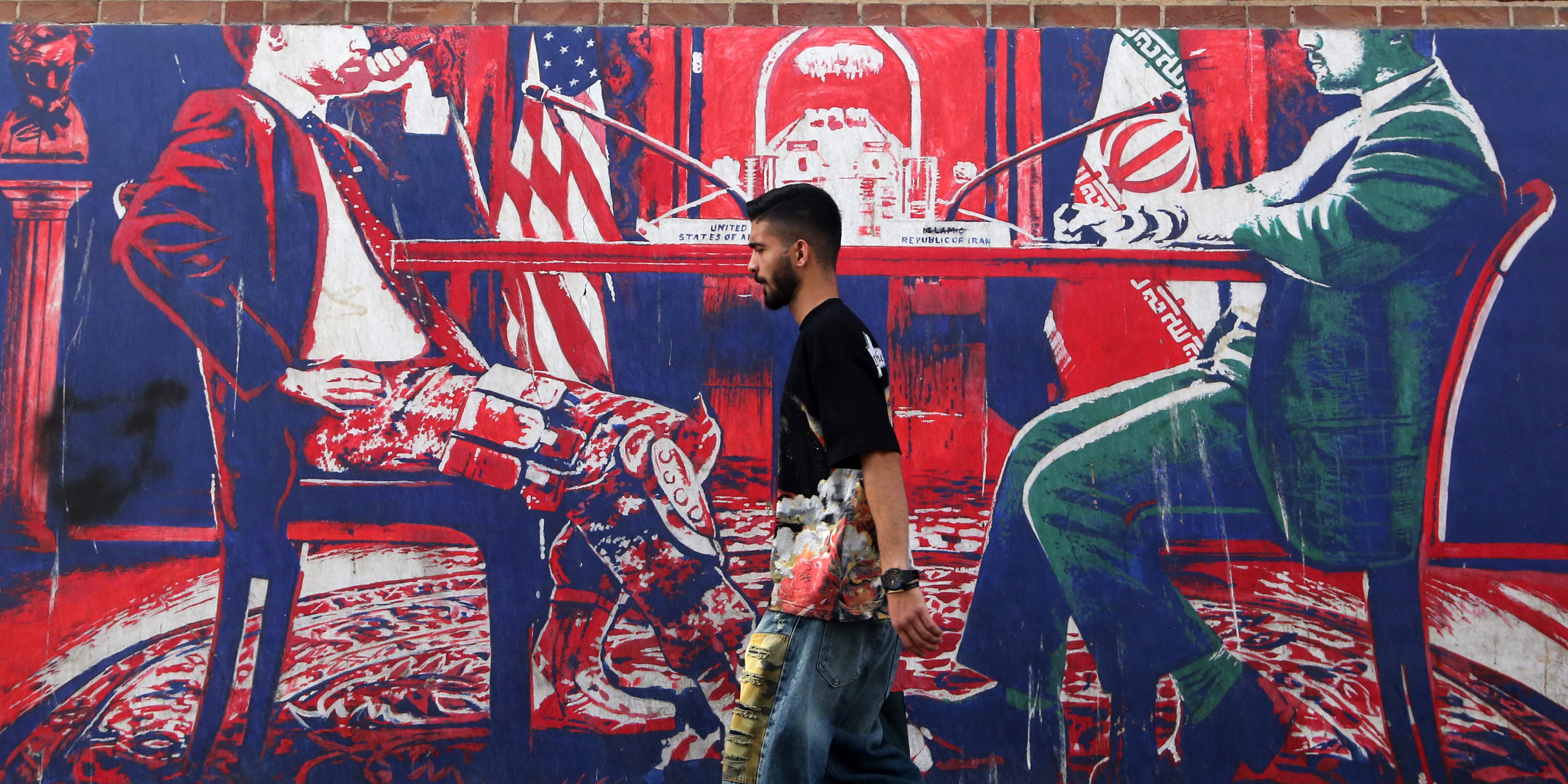 A man passes a mural in Tehran, Iran on June 18, 2026, following the signing of a memorandum of understanding between the United States and Iran.