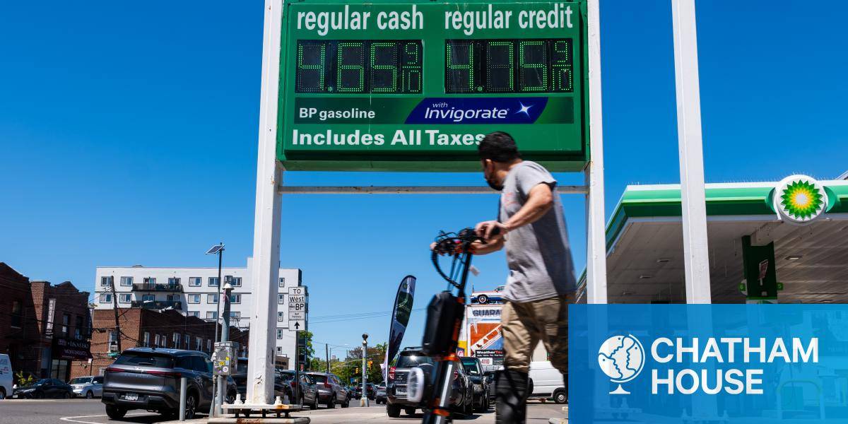 A man on a scooter in front of gas prices in New York City