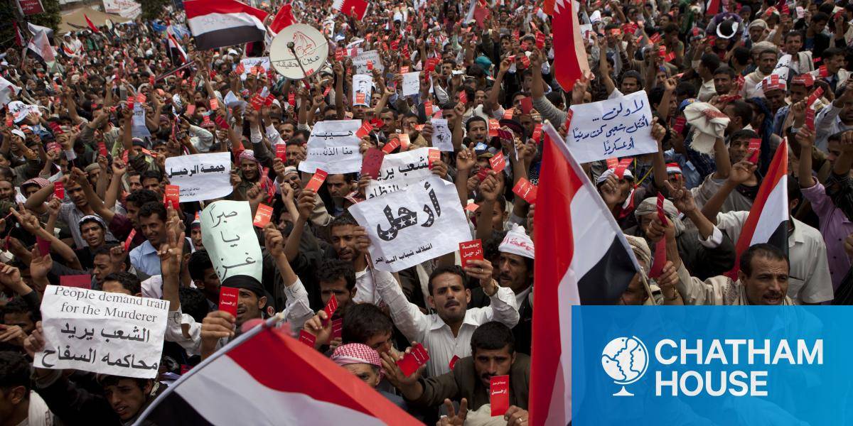 Crowds of people protesting holding Yemeni flags.