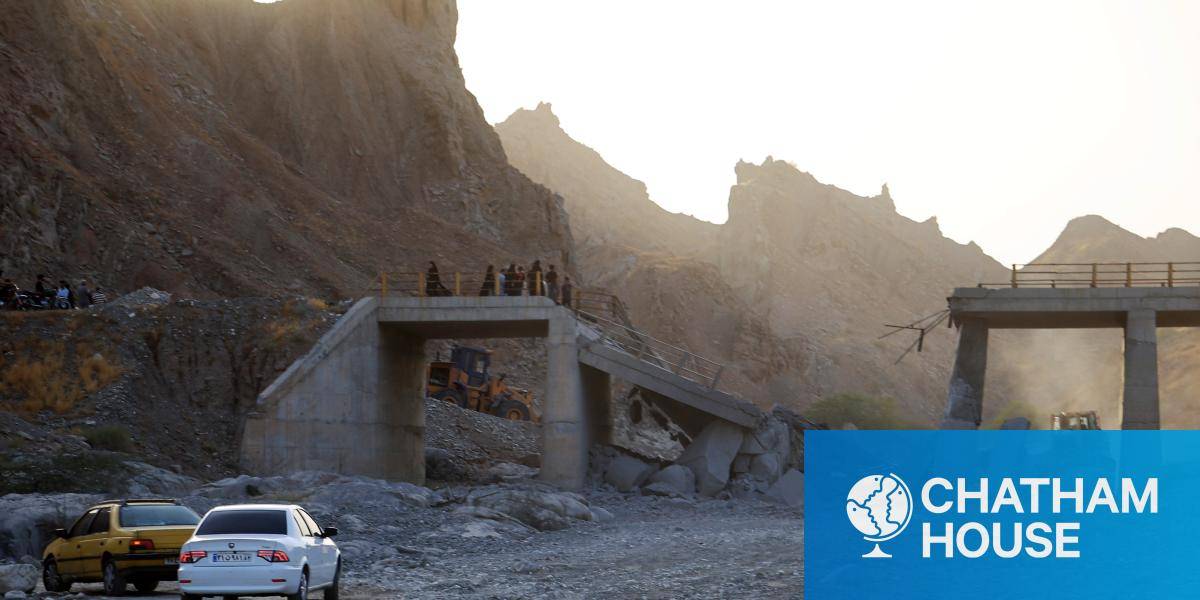 A bridge collapsed after a missile strike, with two cars parked nearby