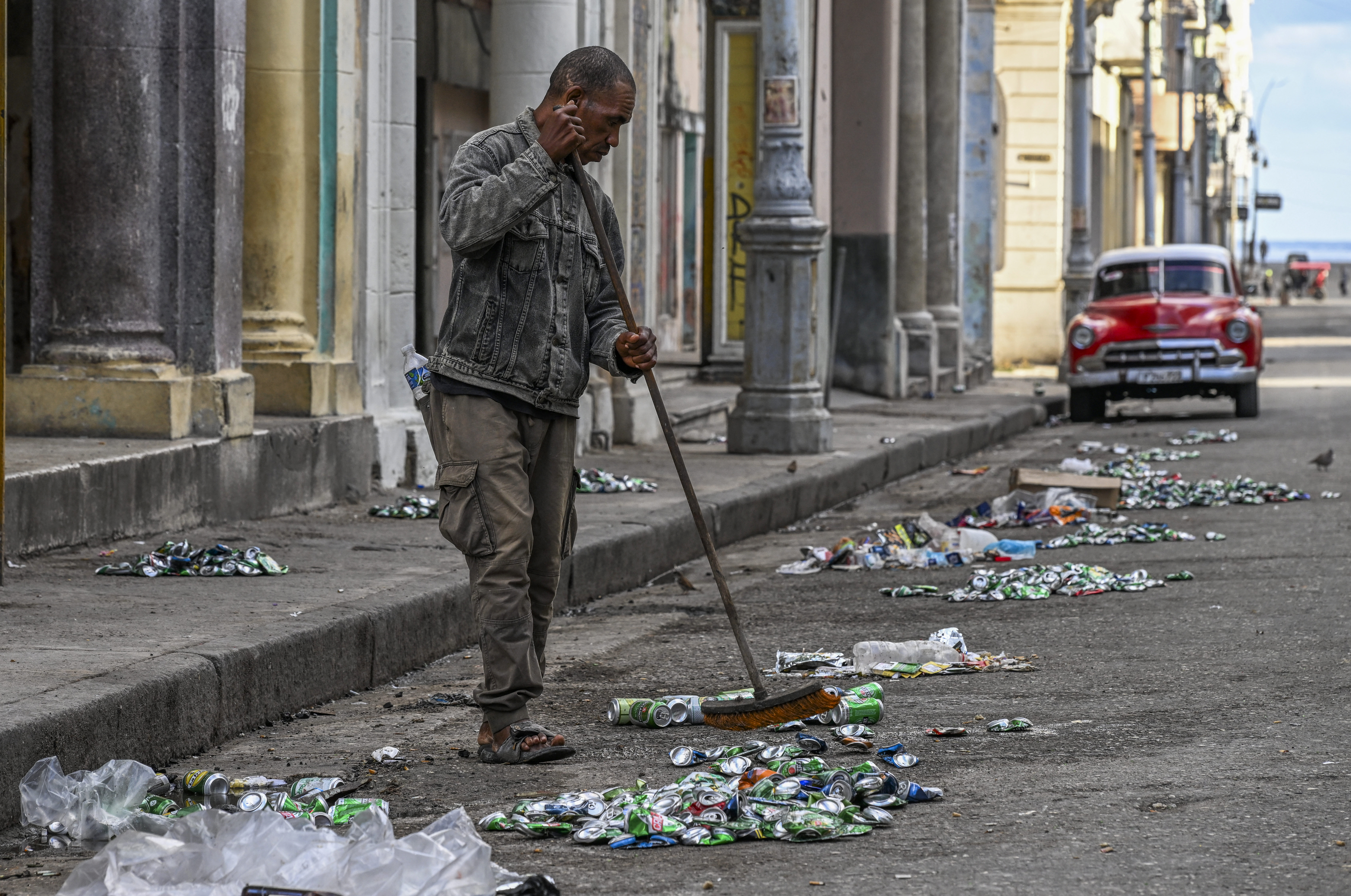 A man sweeps a street during a national blackout in Havana on March 22, 2026. A power outage struck the entire island of Cuba on March 21 the energy ministry said, in the second nationwide blackout in less than a week as its grid struggles under a US oil blockade. (Photo by YAMIL LAGE / AFP via Getty Images)